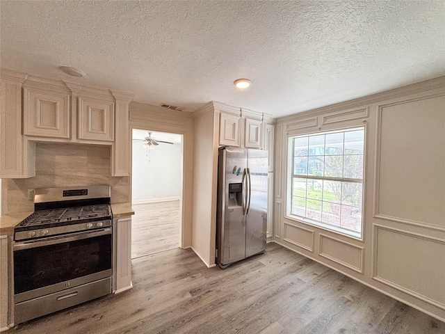 kitchen featuring ceiling fan, cream cabinets, stainless steel appliances, and light wood-type flooring