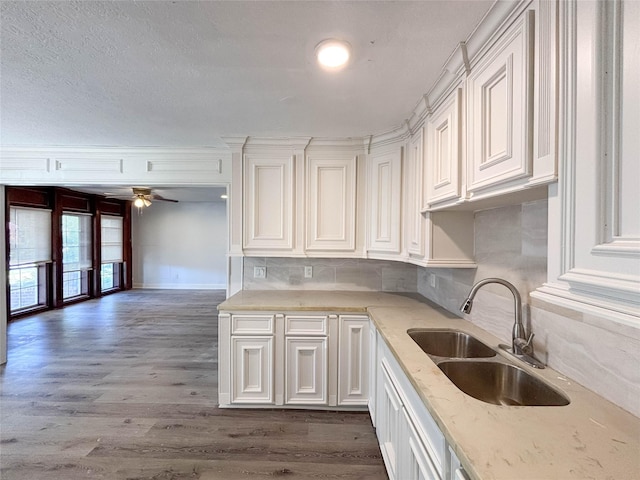 kitchen with backsplash, dark wood-style floors, white cabinets, a ceiling fan, and a sink