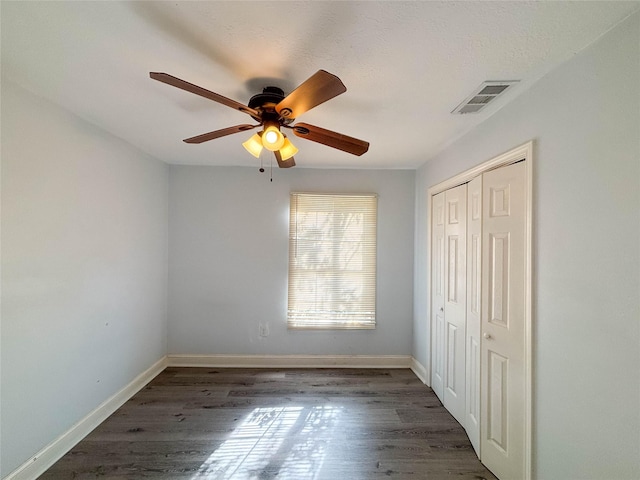 unfurnished bedroom featuring ceiling fan, dark hardwood / wood-style floors, and a closet