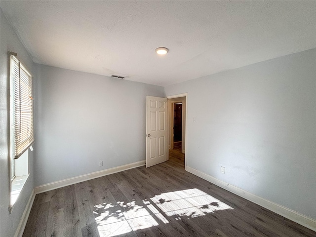 empty room with visible vents, baseboards, and wood finished floors