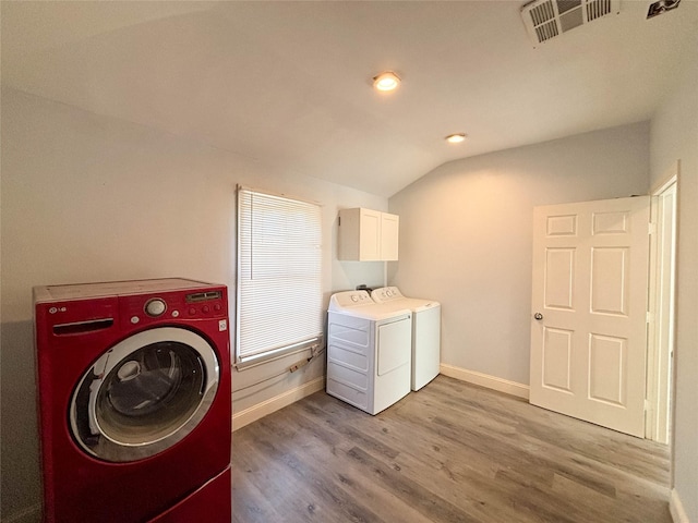 laundry area with cabinets, light wood-type flooring, and washing machine and dryer