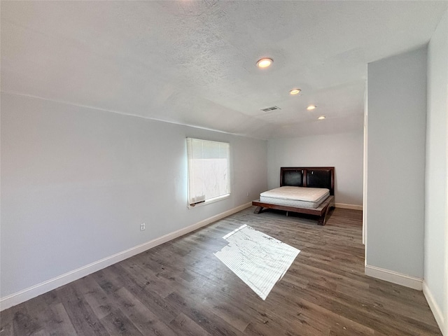 unfurnished bedroom featuring visible vents, a textured ceiling, dark wood finished floors, recessed lighting, and baseboards