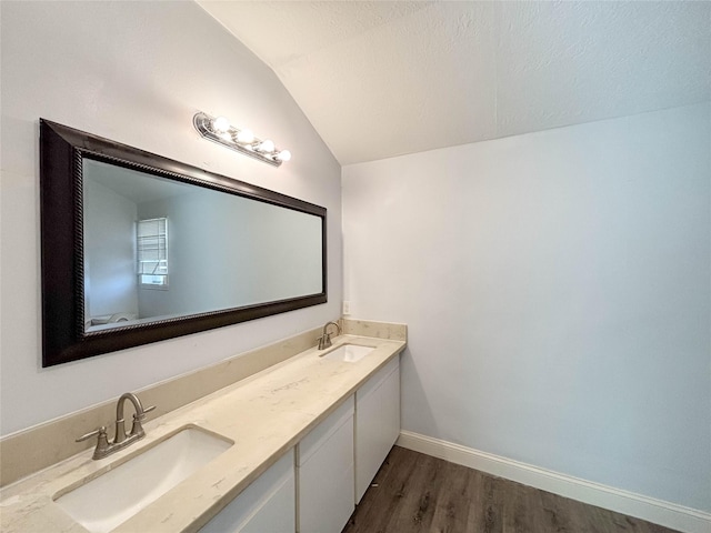 bathroom featuring lofted ceiling, wood finished floors, baseboards, and a sink