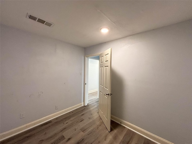 empty room featuring wood finished floors, visible vents, and baseboards