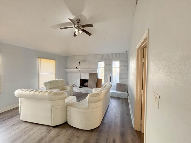 living area with wood finished floors, baseboards, a fireplace, ceiling fan, and vaulted ceiling