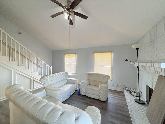 living room featuring vaulted ceiling, dark hardwood / wood-style floors, a brick fireplace, and ceiling fan