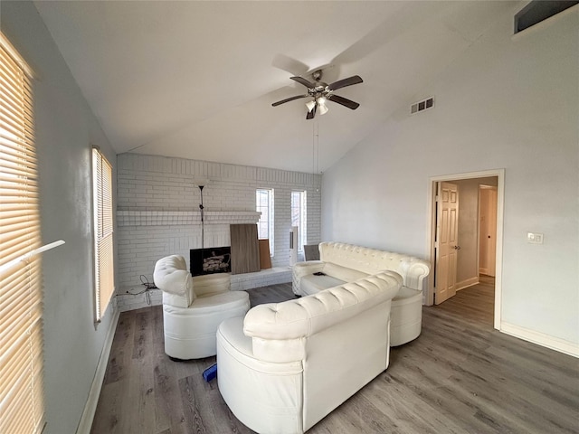 living room featuring ceiling fan, wood-type flooring, lofted ceiling, and a brick fireplace