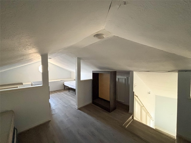 additional living space with a textured ceiling, wood finished floors, and vaulted ceiling