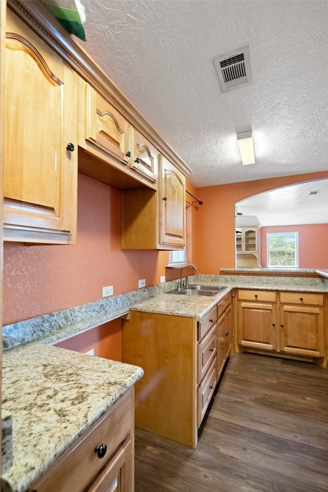 kitchen with dark hardwood / wood-style flooring, kitchen peninsula, sink, and light brown cabinetry