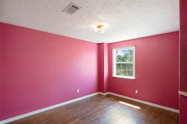 spare room featuring a textured ceiling and hardwood / wood-style flooring