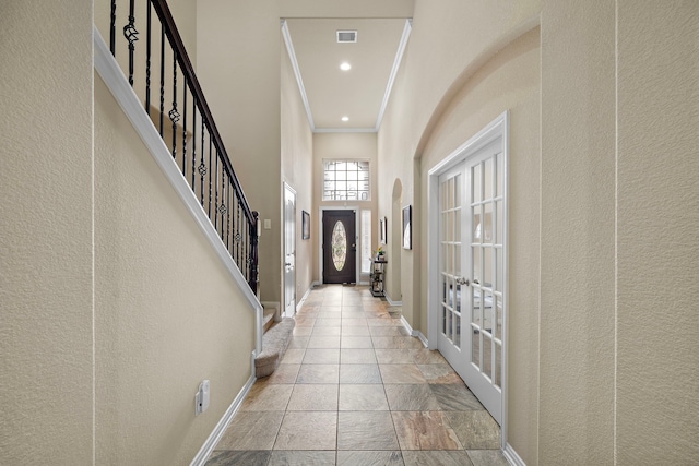 foyer featuring crown molding, french doors, and a towering ceiling