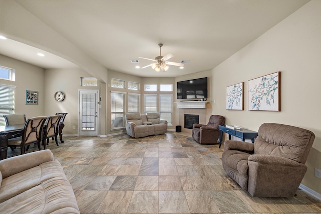 living room with ceiling fan, a tile fireplace, and a wealth of natural light