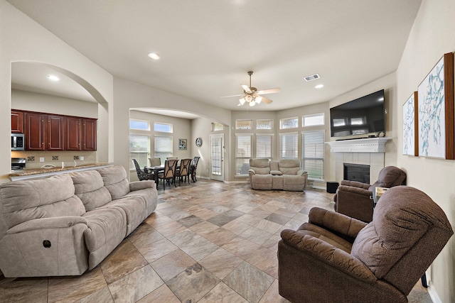 living room featuring a tiled fireplace and ceiling fan