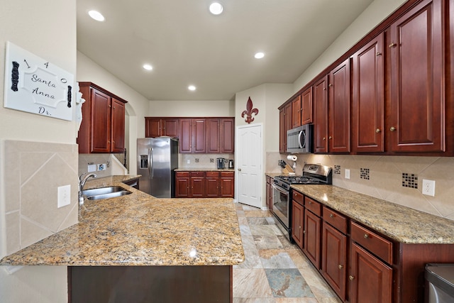 kitchen featuring sink, light stone counters, tasteful backsplash, appliances with stainless steel finishes, and kitchen peninsula