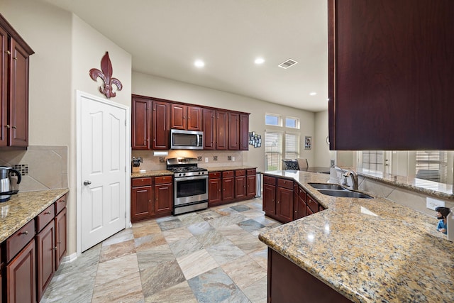 kitchen with light stone countertops, appliances with stainless steel finishes, sink, and decorative backsplash