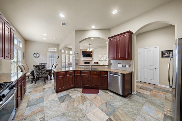 kitchen with appliances with stainless steel finishes, tasteful backsplash, sink, ceiling fan, and kitchen peninsula