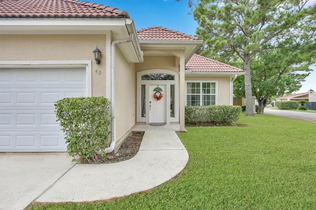 entrance to property featuring a lawn and a garage