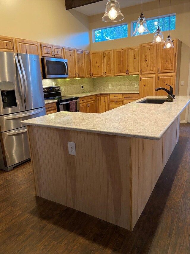 kitchen with a large island, sink, hanging light fixtures, stainless steel appliances, and a high ceiling