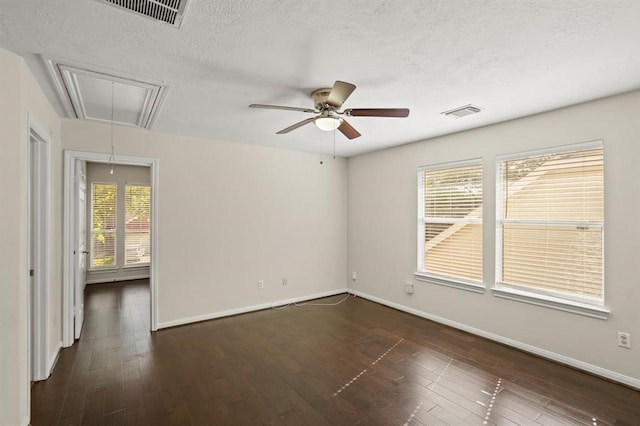 empty room with visible vents, a textured ceiling, wood-type flooring, baseboards, and attic access