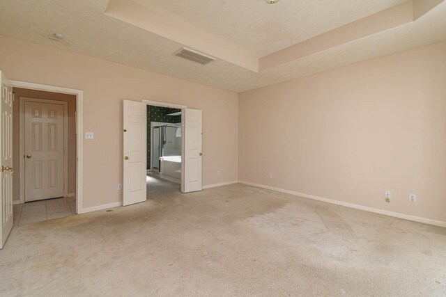 unfurnished bedroom with a tray ceiling and light colored carpet