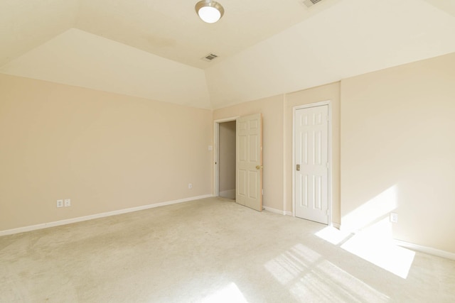 unfurnished bedroom featuring a closet, light colored carpet, and lofted ceiling