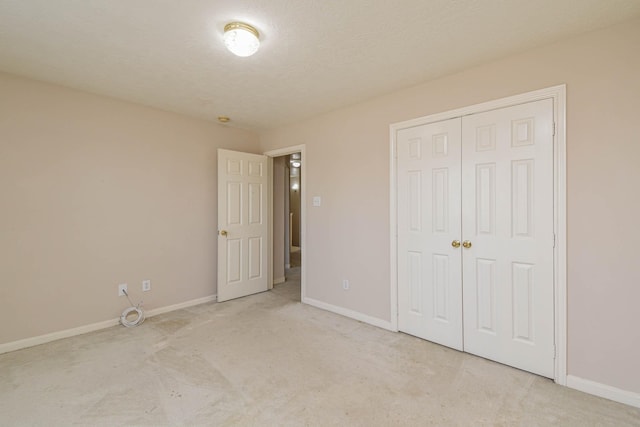 unfurnished bedroom with light colored carpet, a textured ceiling, and a closet