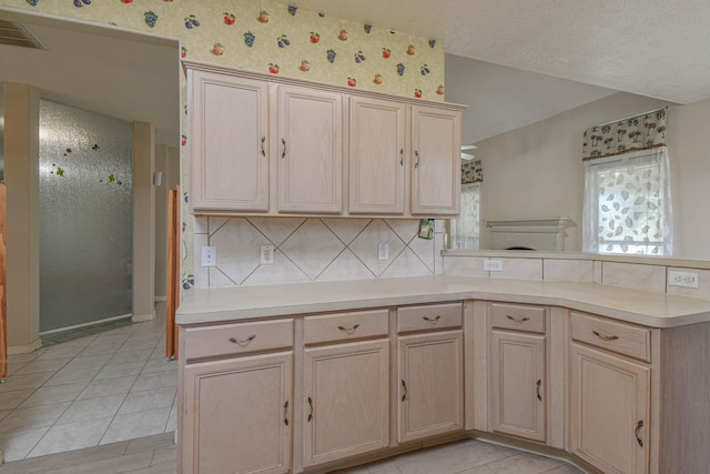 kitchen featuring tasteful backsplash, kitchen peninsula, light brown cabinets, and light tile patterned floors