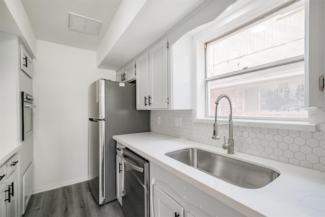 kitchen with white cabinetry, sink, dark hardwood / wood-style flooring, decorative backsplash, and stainless steel appliances