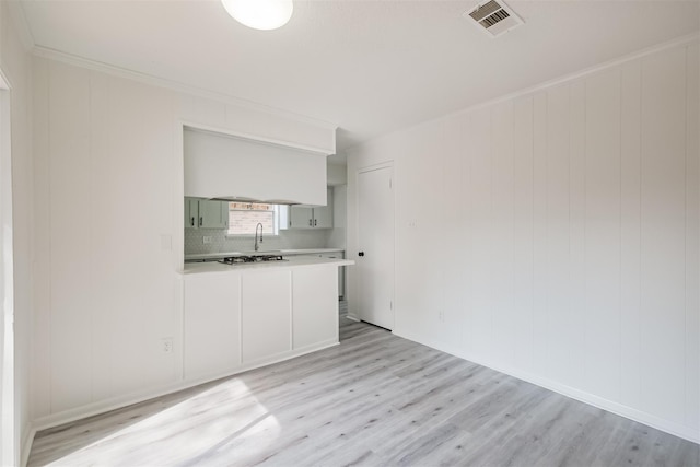 empty room with ornamental molding and light hardwood / wood-style flooring