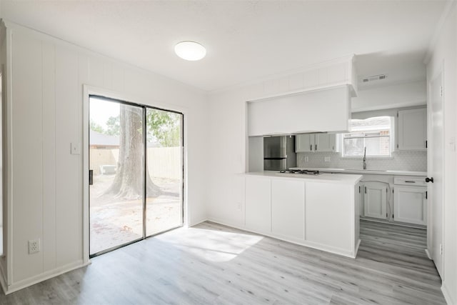 kitchen with sink, plenty of natural light, kitchen peninsula, and stainless steel refrigerator