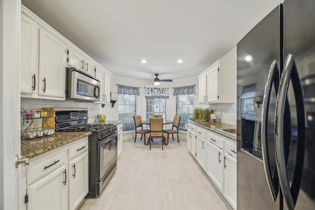 kitchen featuring backsplash, dark stone countertops, white cabinets, and appliances with stainless steel finishes