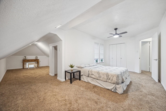 carpeted bedroom featuring ceiling fan, lofted ceiling, a textured ceiling, and a closet