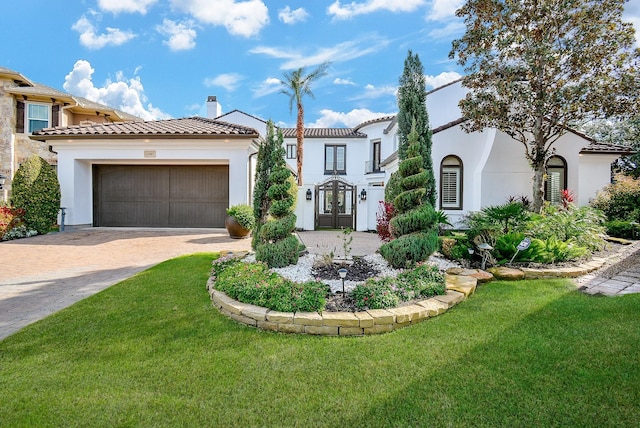 mediterranean / spanish-style house with a garage, a front lawn, and french doors