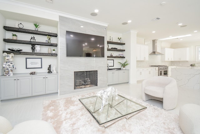 living room with a tile fireplace and crown molding