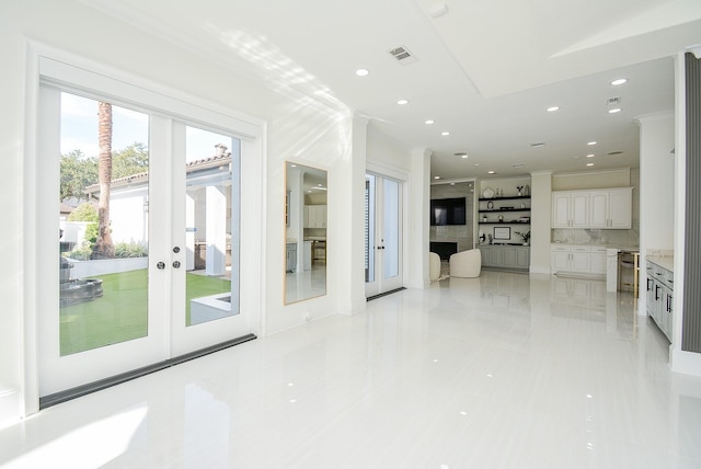 interior space with french doors, ornamental molding, a premium fireplace, and light tile patterned floors