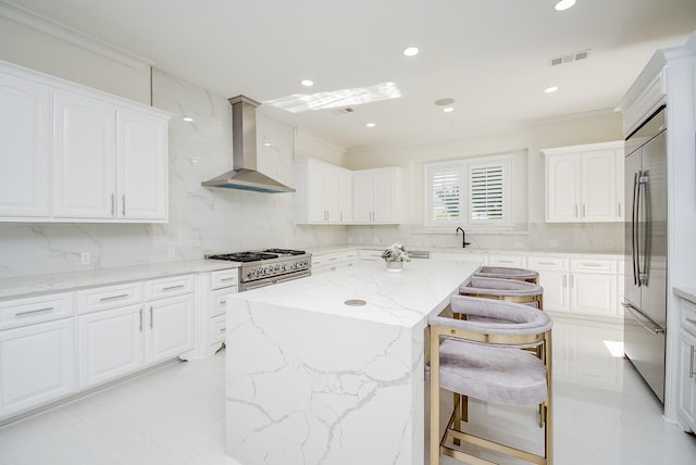 kitchen featuring white cabinetry, wall chimney range hood, high quality appliances, and a kitchen island