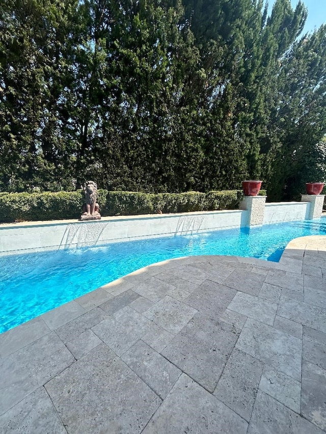 view of swimming pool with pool water feature and a patio