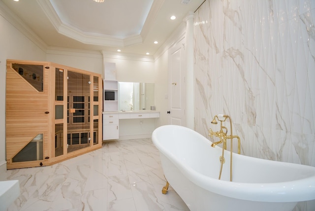 bathroom with tile walls, a bathtub, vanity, a raised ceiling, and crown molding