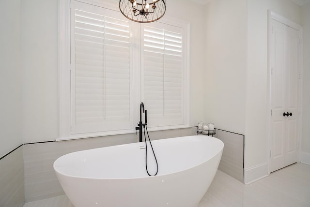 bathroom featuring tile patterned flooring, a bathing tub, and a notable chandelier