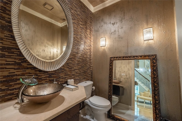 bathroom with tasteful backsplash, sink, toilet, and ornamental molding