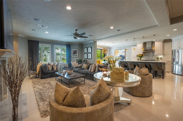 living room featuring ceiling fan, a textured ceiling, and ornamental molding