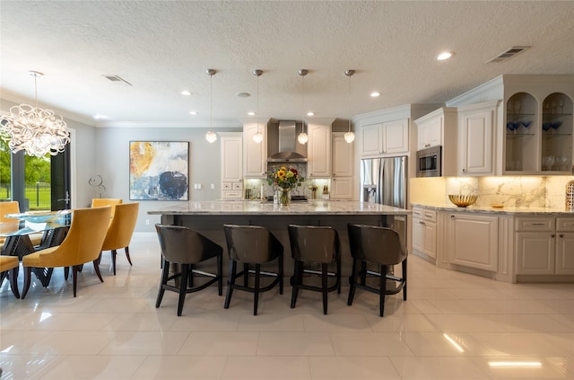 kitchen featuring light stone countertops, hanging light fixtures, a large island, and wall chimney exhaust hood