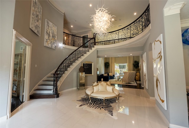 entrance foyer with a chandelier, a towering ceiling, crown molding, and light tile patterned flooring