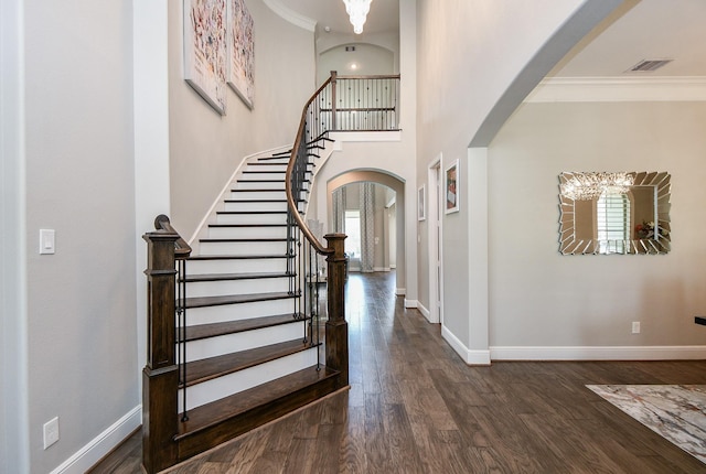 entrance foyer featuring dark hardwood / wood-style flooring, ornamental molding, and an inviting chandelier