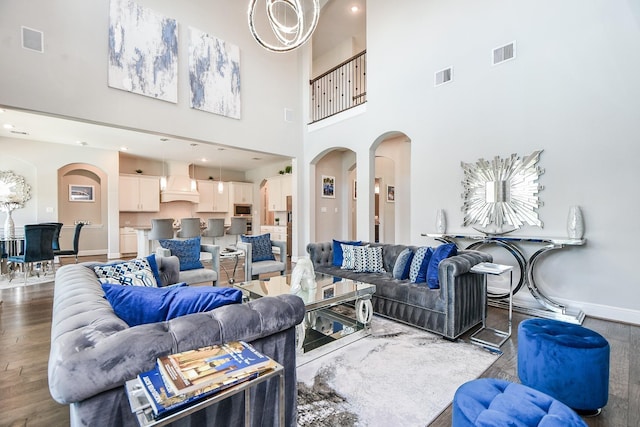 living room featuring a chandelier, a high ceiling, and dark wood-type flooring