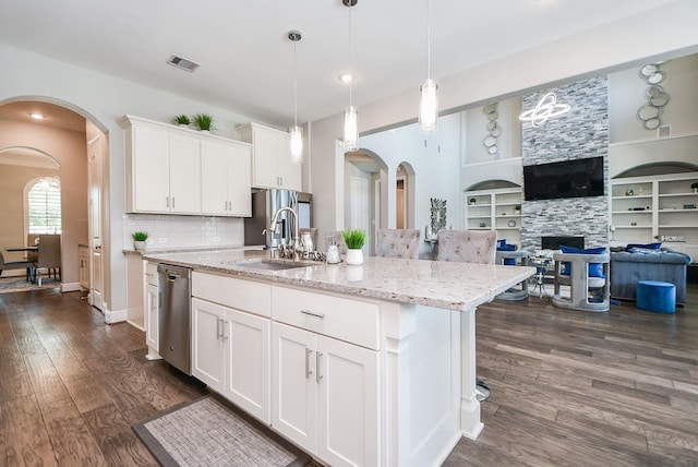 kitchen featuring dishwasher, a center island with sink, built in features, a fireplace, and white cabinetry