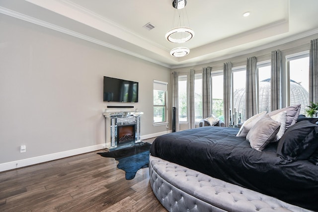 bedroom with wood-type flooring, ornamental molding, and a tray ceiling