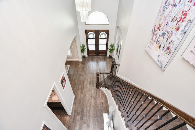 entrance foyer featuring an inviting chandelier, dark hardwood / wood-style flooring, a towering ceiling, and french doors