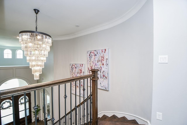 stairs featuring a notable chandelier and crown molding