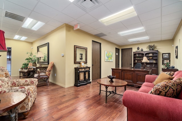 living room featuring a paneled ceiling, crown molding, and dark wood-type flooring